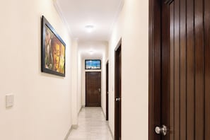 A hallway with a door on the right, a painting on the left, and a ceiling light. - FabHotel Metro Inn Kalkaji (New Delhi)