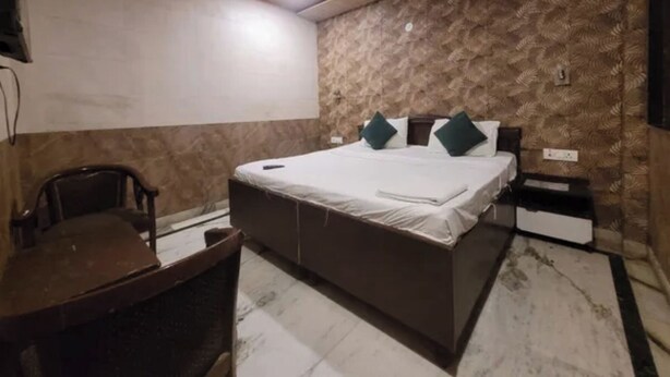 Quarto com cama, escrivaninha, cadeira, ventilador de teto e parede com padrão.