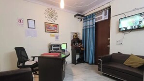 Uma área de recepção com balcão, computador, cadeira e sofá.