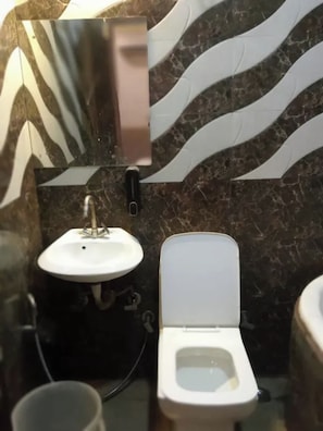 A bathroom with a white sink, a toilet, and a mirror. - Fabhotel Metro Inn Kalkaji (New Delhi)