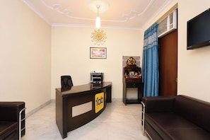 A hotel reception area with a reception desk, a sofa, a wall-mounted television, and a ceiling light fixture. - FabHotel Metro Inn Kalkaji (New Delhi)