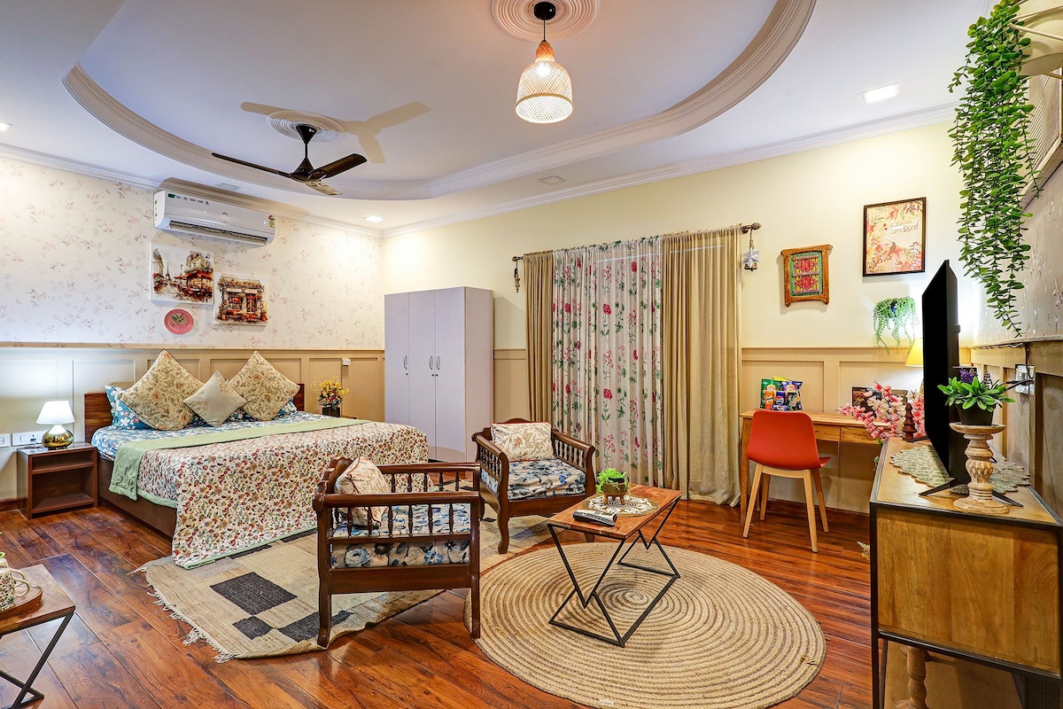 A hotel room with a bed, a desk, a chair, a ceiling fan, and a window with curtains.