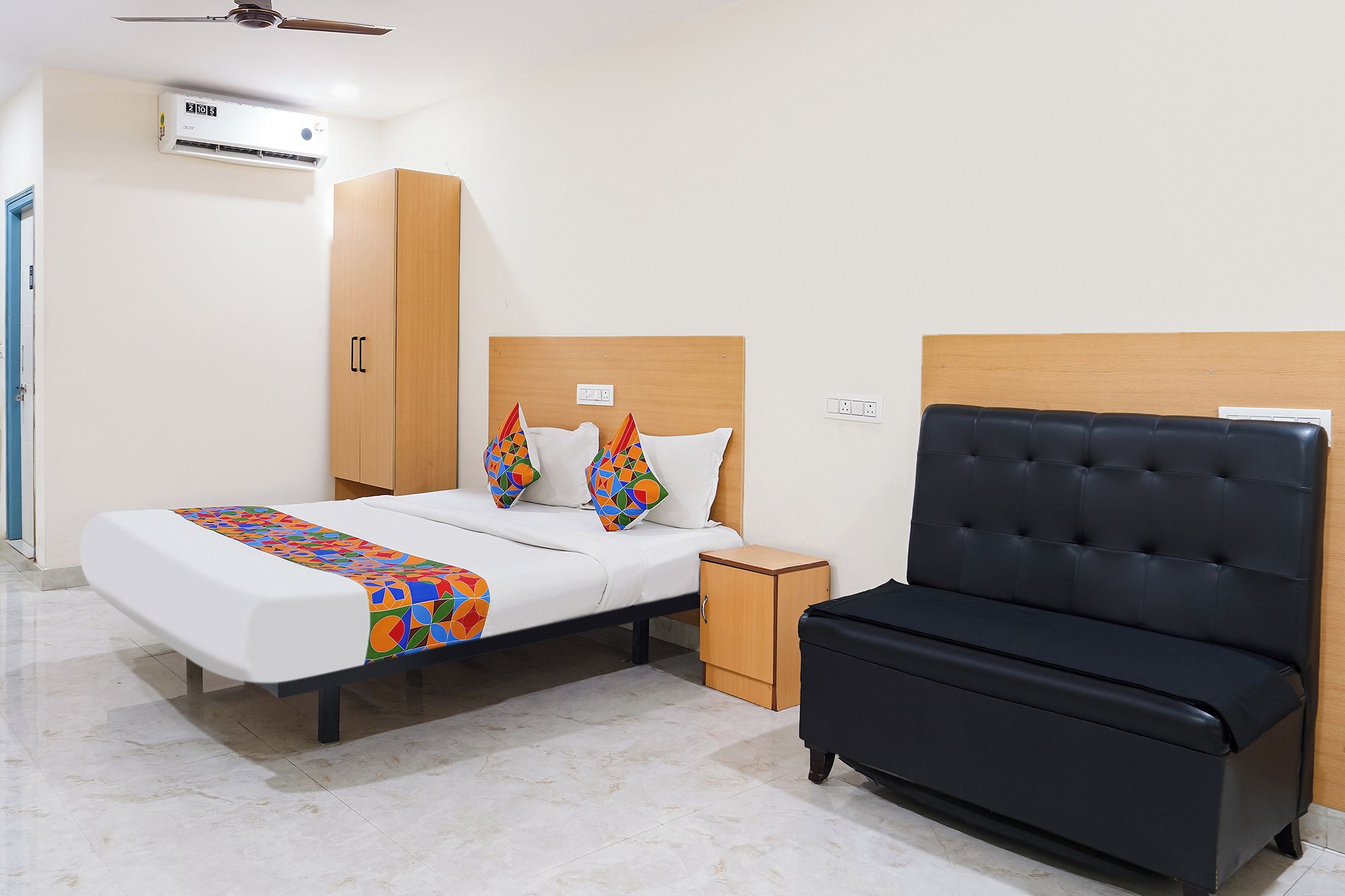 A hotel room with a bed, a bedside table, a wardrobe, and a black sofa.