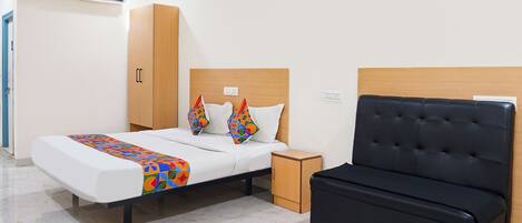 A hotel room with a bed, a bedside table, a wardrobe, and a black sofa.