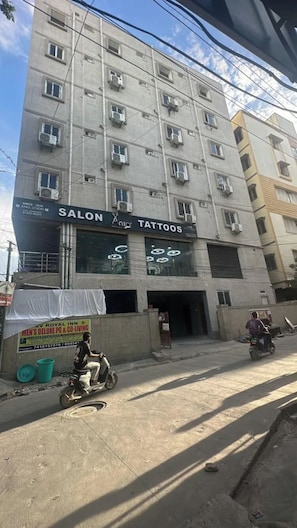 Un edificio de varios pisos con un letrero en la planta baja para un salón de belleza y una tienda de tatuajes.