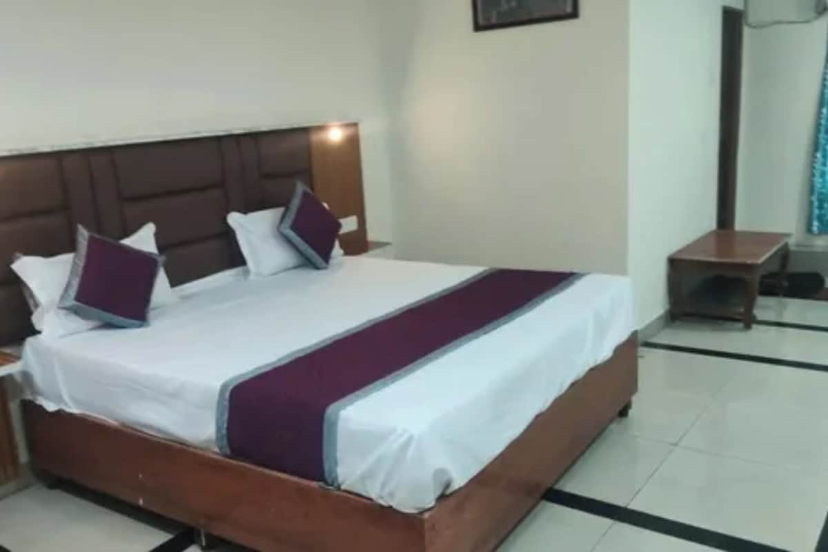 Una habitación de hotel con una cama grande, cabecera de madera y una mesita de noche pequeña.
