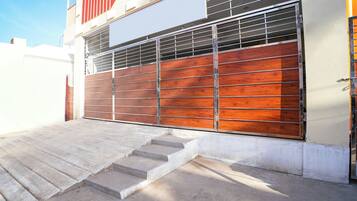 Una entrada protegida por una cerca de metal y un panel de madera, que da a una escalera de hormigón.