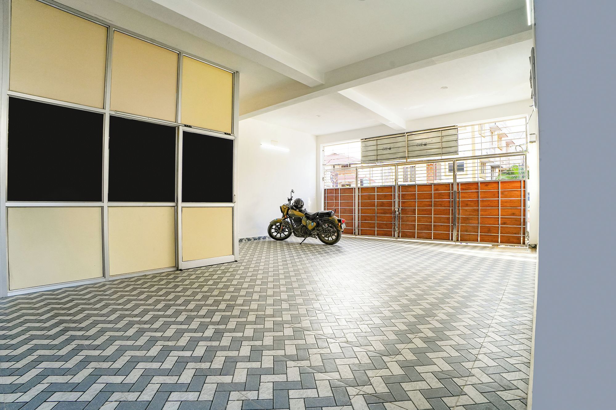 A motorcycle parked in a garage with a tiled floor and a large garage door.