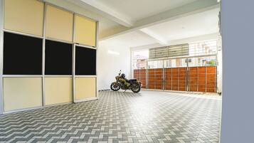A motorcycle parked in a garage with a tiled floor and a large garage door.