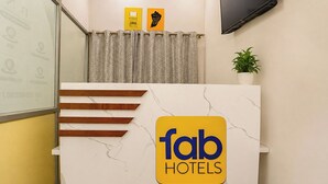 Una recepción con encimera de mármol, el logotipo de 'fab hotels' y una planta en maceta en la pared.