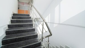 Una escalera con barandilla de metal y pared blanca.