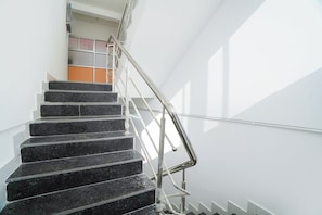 Una escalera con barandilla de metal y pared blanca.