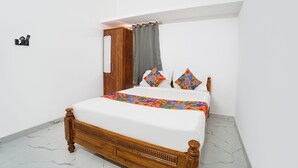 Un dormitorio con una cama de madera, ropa de cama blanca y almohadas geométricas de colores.