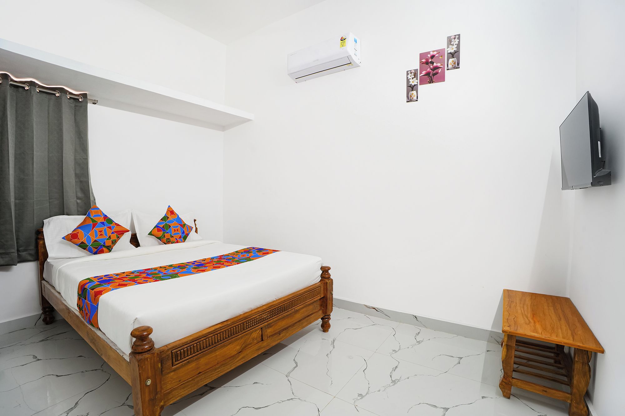 Un dormitorio con cama, una mesita de madera, televisor y aire acondicionado.