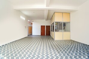 A hallway with patterned flooring, wooden doors, and a glass-walled office area.