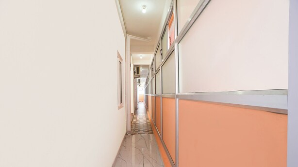 Un pasillo con suelo de baldosas, una pared con un panel vertical y una puerta al final.
