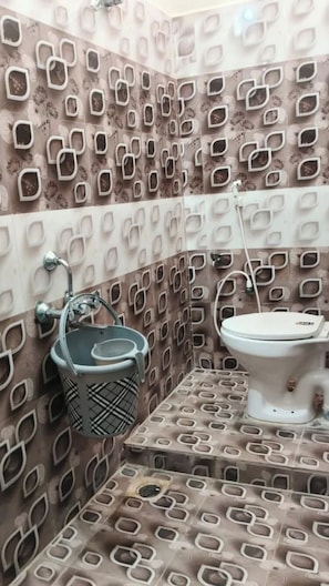 Un baño con paredes con diseño, un inodoro, un lavabo con una cesta y una zona de ducha.