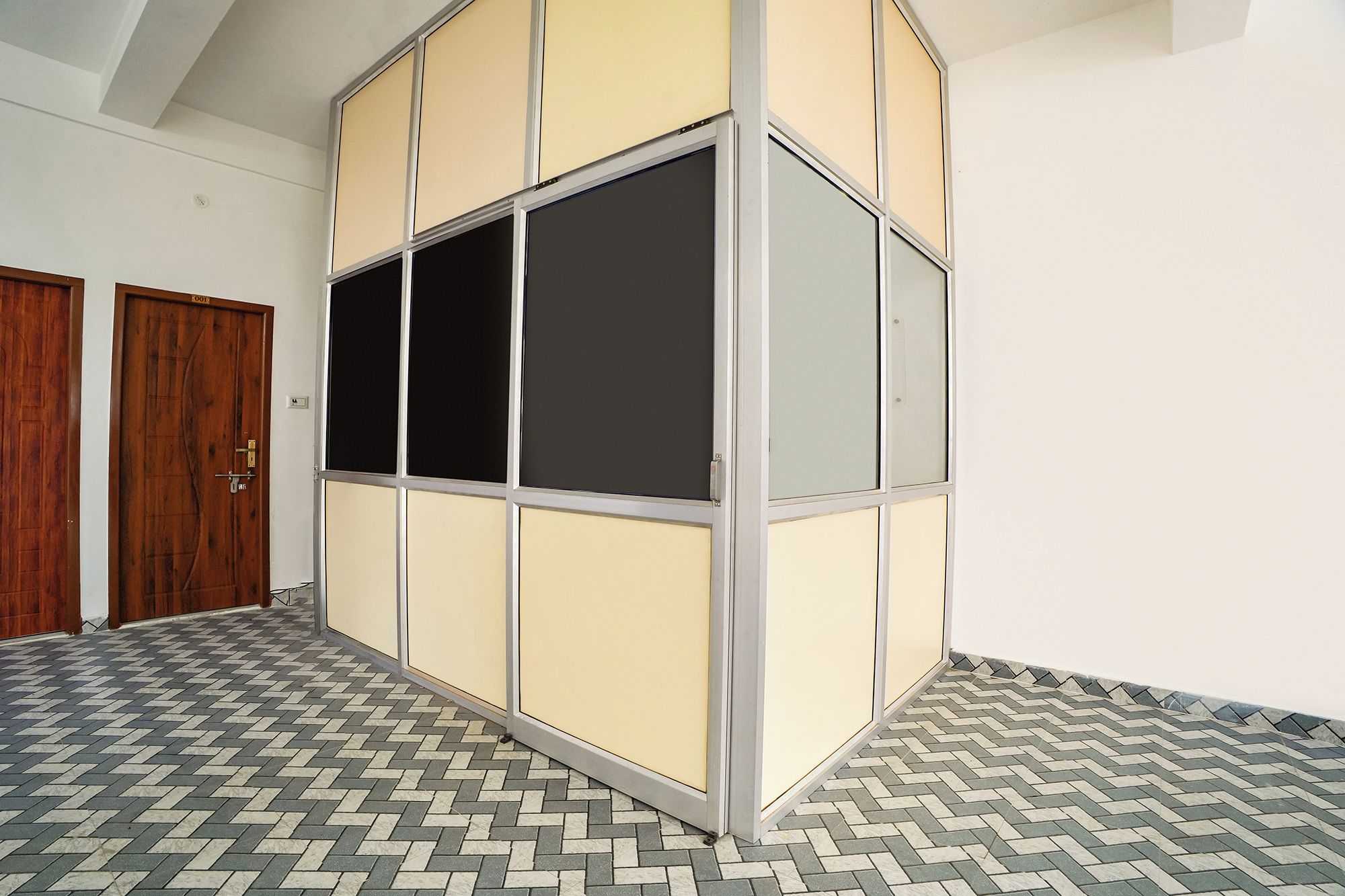 Una habitación con piso de diseño espiga, una puerta de madera y un separador con un ventanal grande.