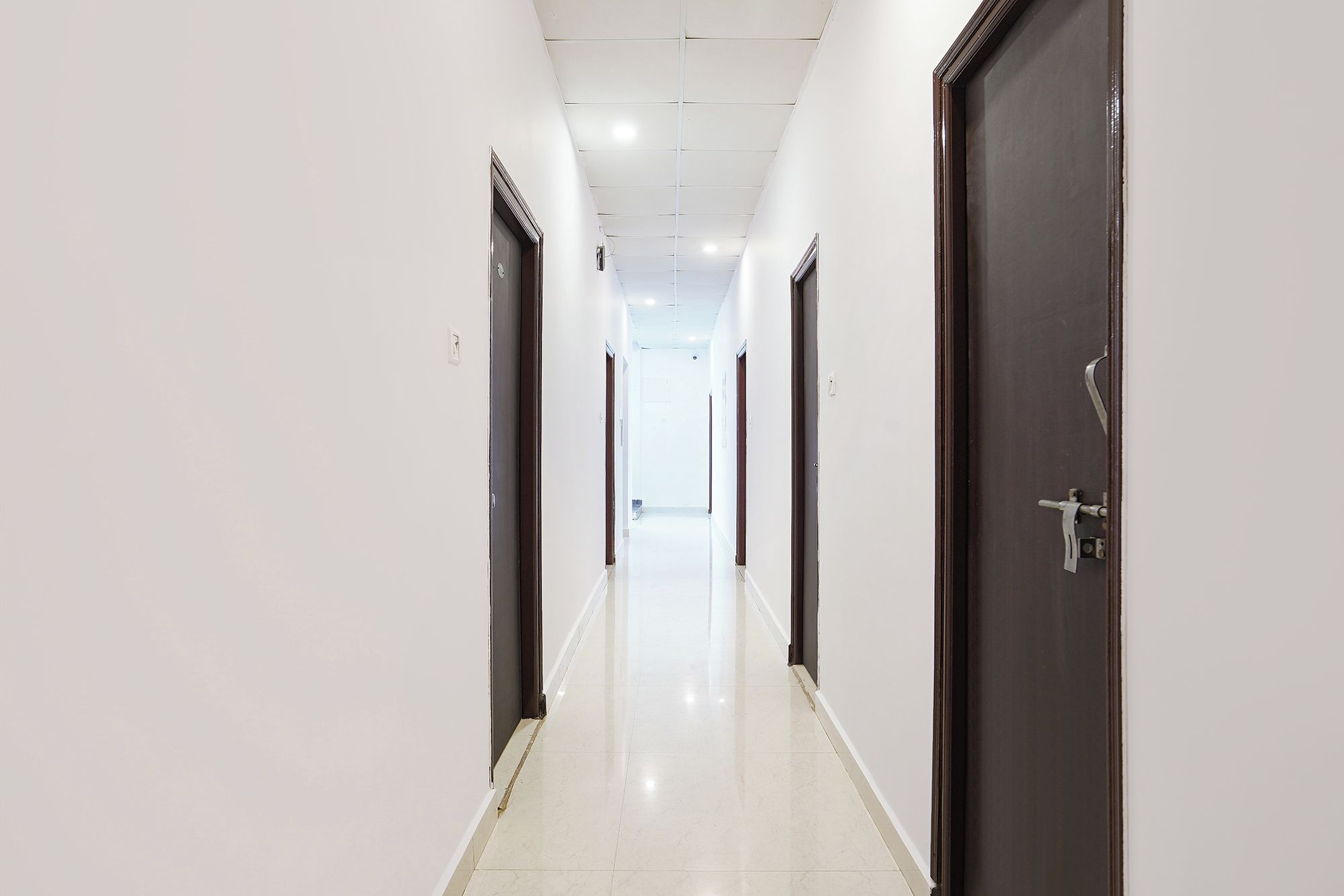 Corredor com portas em ambos os lados, levando a um quarto claro no final.