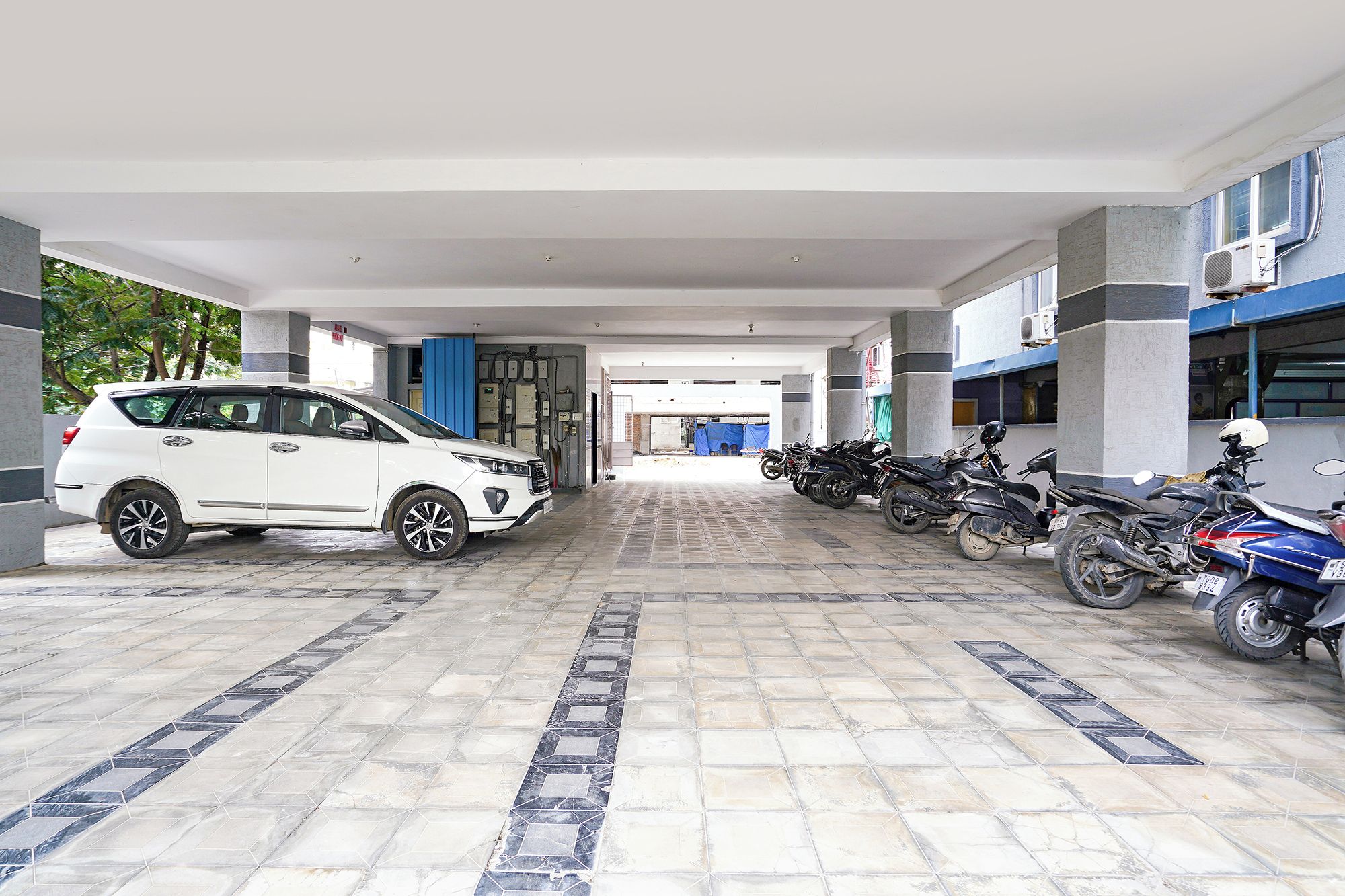 Área de estacionamento coberta com um SUV branco e várias motocicletas estacionadas.