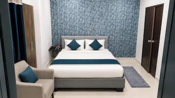 Een slaapkamer met een bed, nachtkastje, stoel en een garderobe.