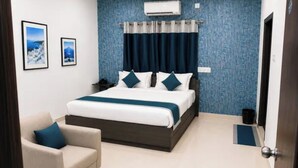 Quarto moderno com uma cama grande, mesa de cabeceira, cadeira e ar condicionado fixado na parede.
