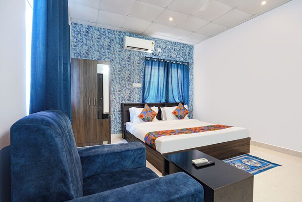 Una habitación de hotel con una cama, un escritorio, una silla y un armario.