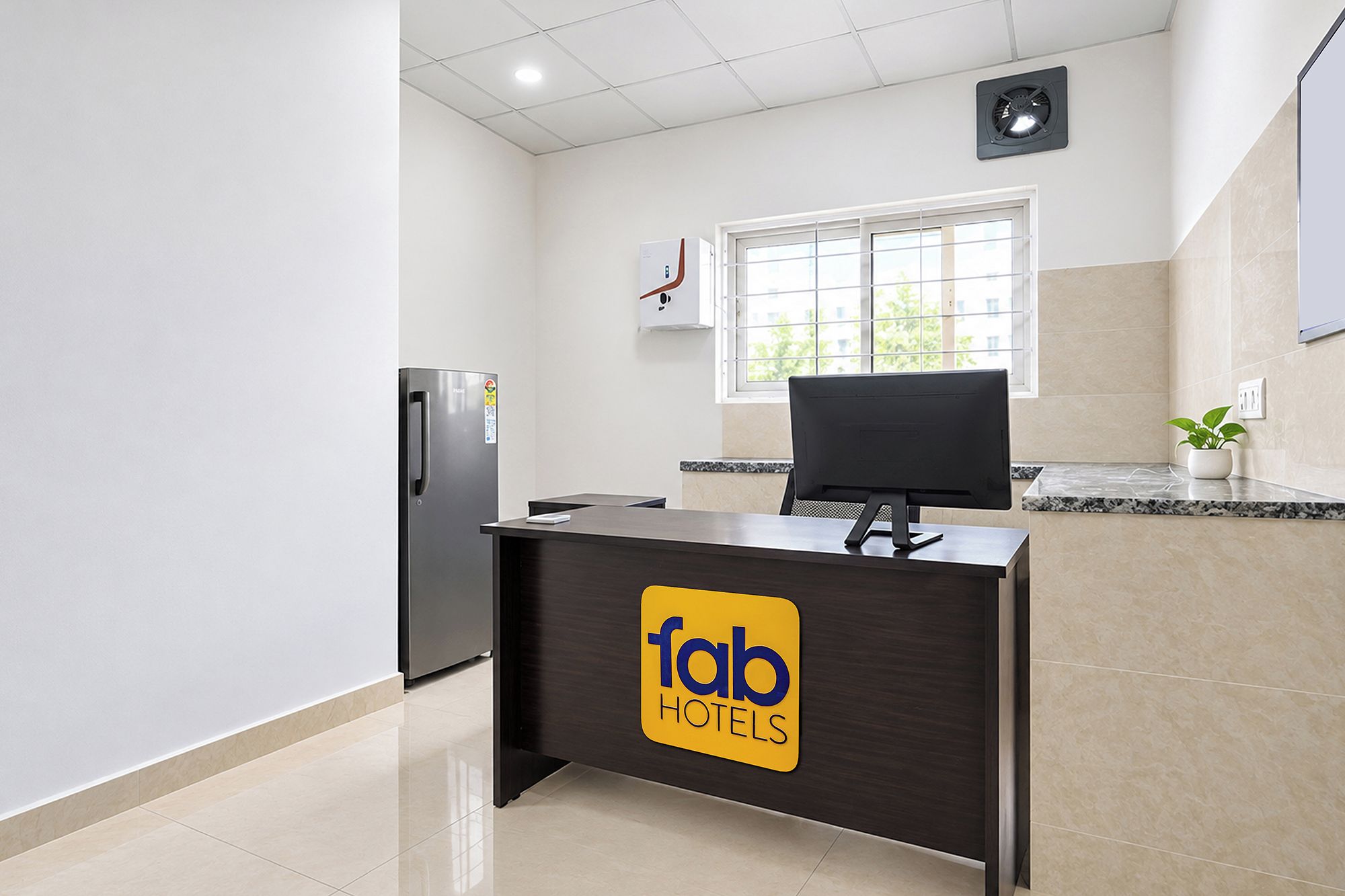 Una reception hotel con un logo, un frigorifero, una finestra e una pianta.