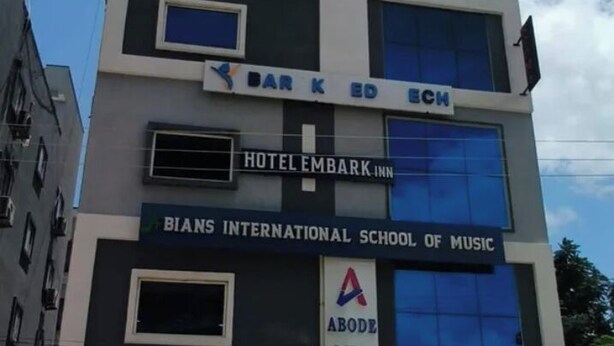Um edifício de vários andares com uma placa indicando 'Hotel Embark' e 'BIANS International School of Music' no terceiro andar.