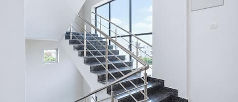 Una escalera moderna con barandillas metálicas que sube a un segundo piso.