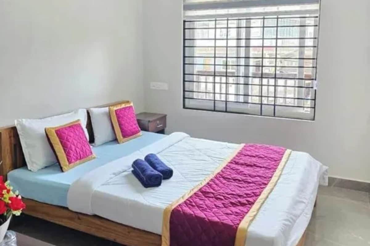 Uma cama de solteiro com cabeceira, janela com grades de metal e um ventilador de teto.