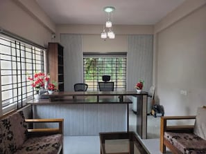 Espaço de refeições moderno com ilha central, disposição de assentos e vista através de grandes janelas.