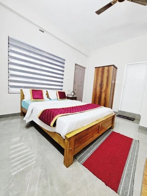 Quarto com cama de madeira, tapete vermelho, guarda-roupa e ventoinha no teto.