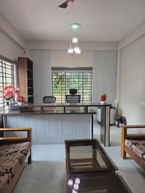 A modern living room with a glass coffee table, a sofa, and a dining area with a kitchen counter.