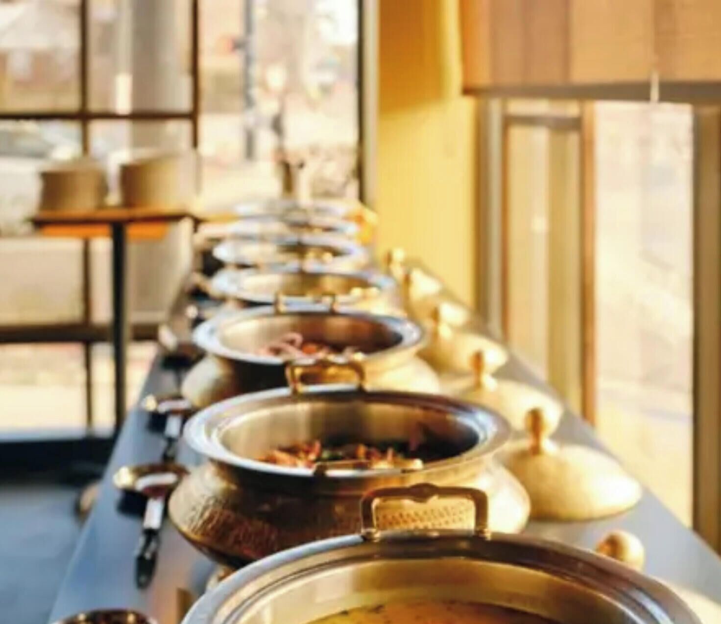 Una barra de buffet con varios platos en recipientes.