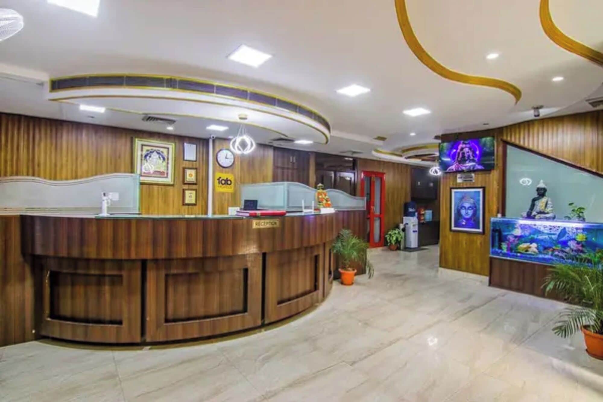 Un espace d’accueil avec un comptoir de réception en bois, une horloge et un écran de télévision.