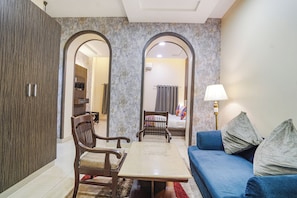 A living room with a sofa, a table, and two chairs. There are two arched doorways leading to other rooms. - FabHotel Rivlet Premium (New Delhi)