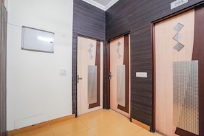 A hallway with three doors, each with a different design, and a whiteboard on the wall. - FabHotel Rivlet Premium (New Delhi)