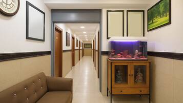 Un pasillo de hotel con un sofá, un acuario, cuadros enmarcados y puertas.