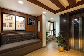 A modern interior with a bench, a potted plant, and an elevator. - FabHotel Rivlet Central Delhi (New Delhi)