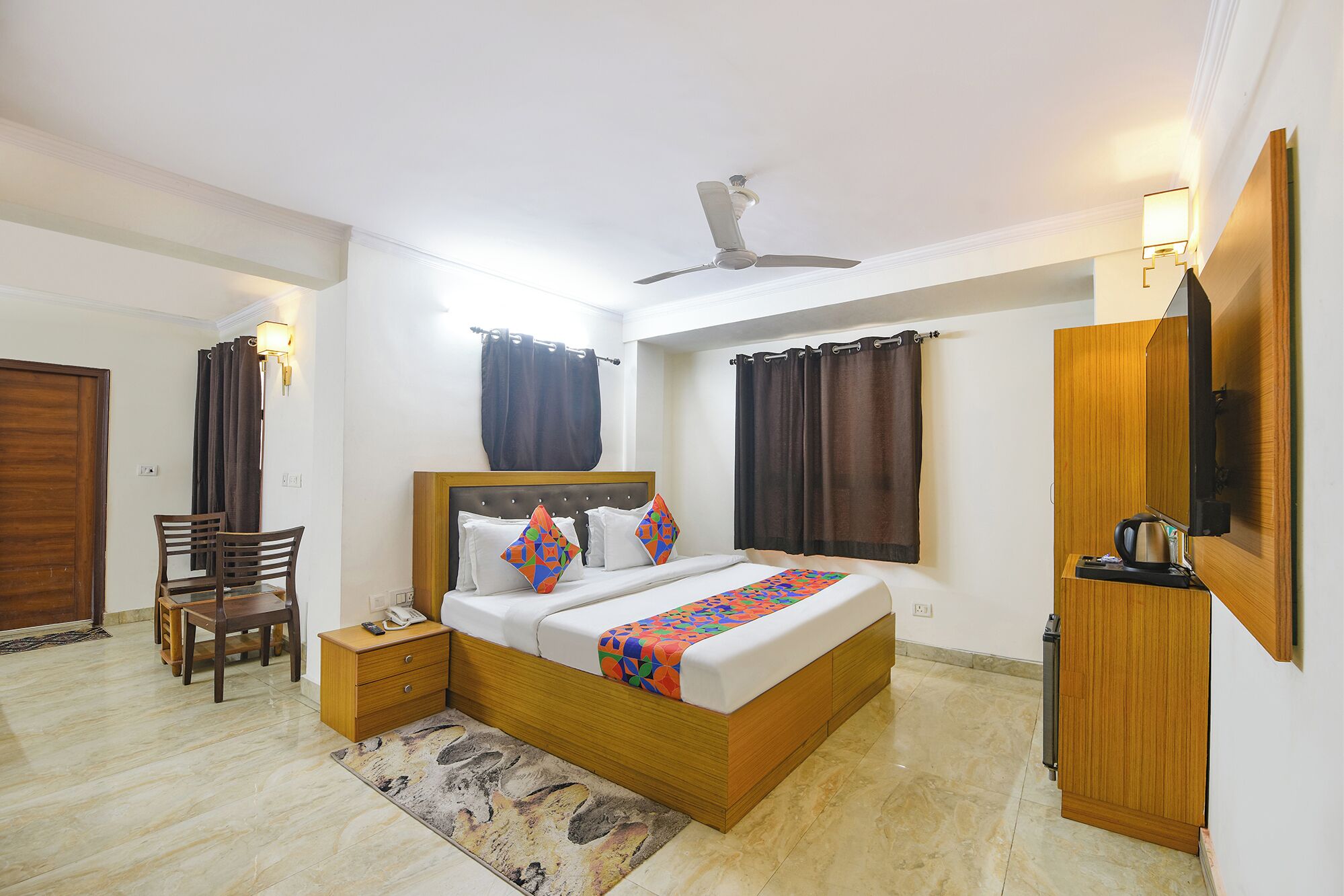 A bedroom with a bed, bedside table, chair, and a ceiling fan.