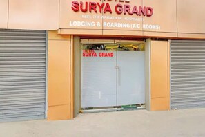 Entrada de un hotel con un cartel que indica Surya Grand, ofreciendo servicios de alojamiento.