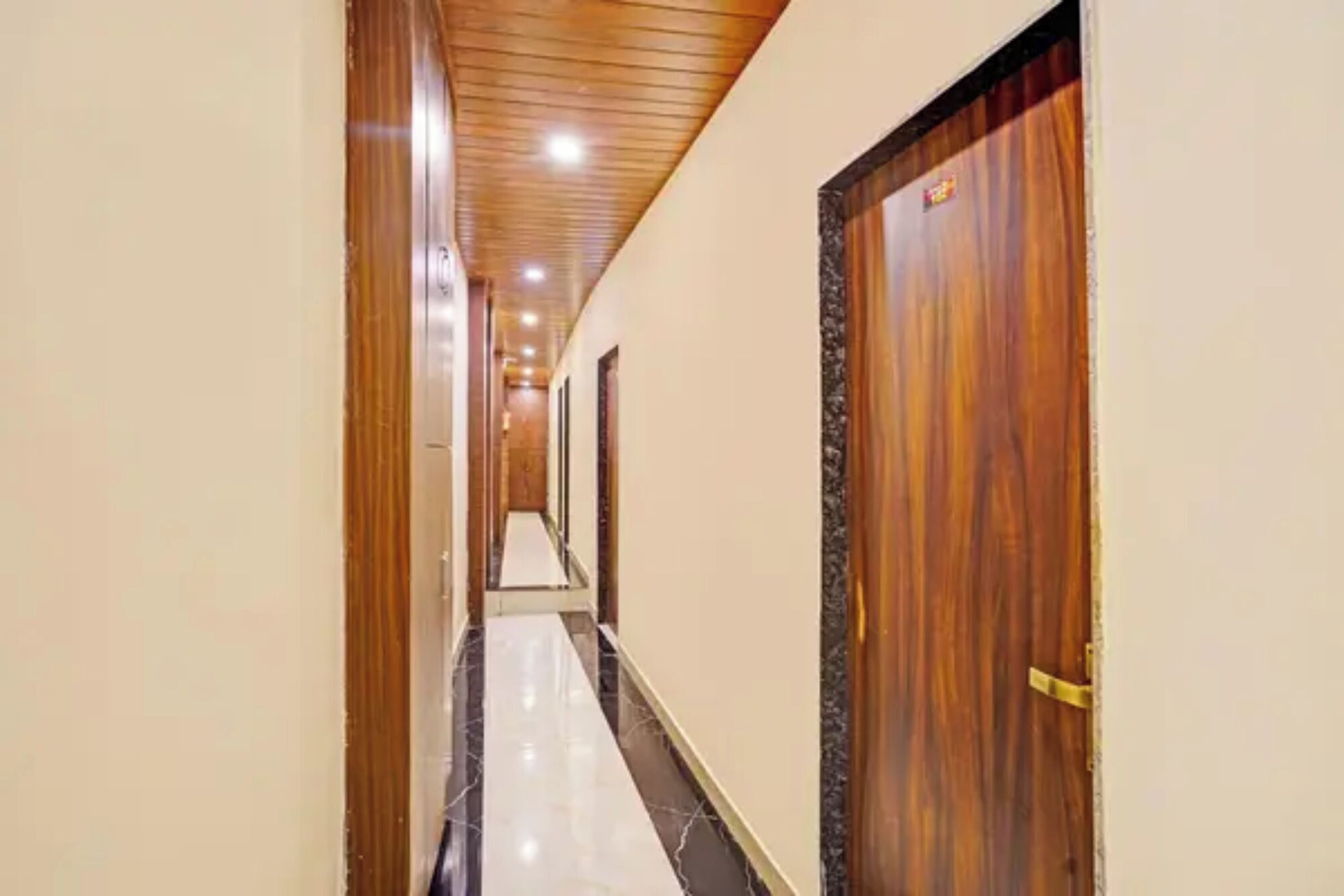 Un pasillo de hotel con puertas de madera, suelo de baldosas y techo de madera.