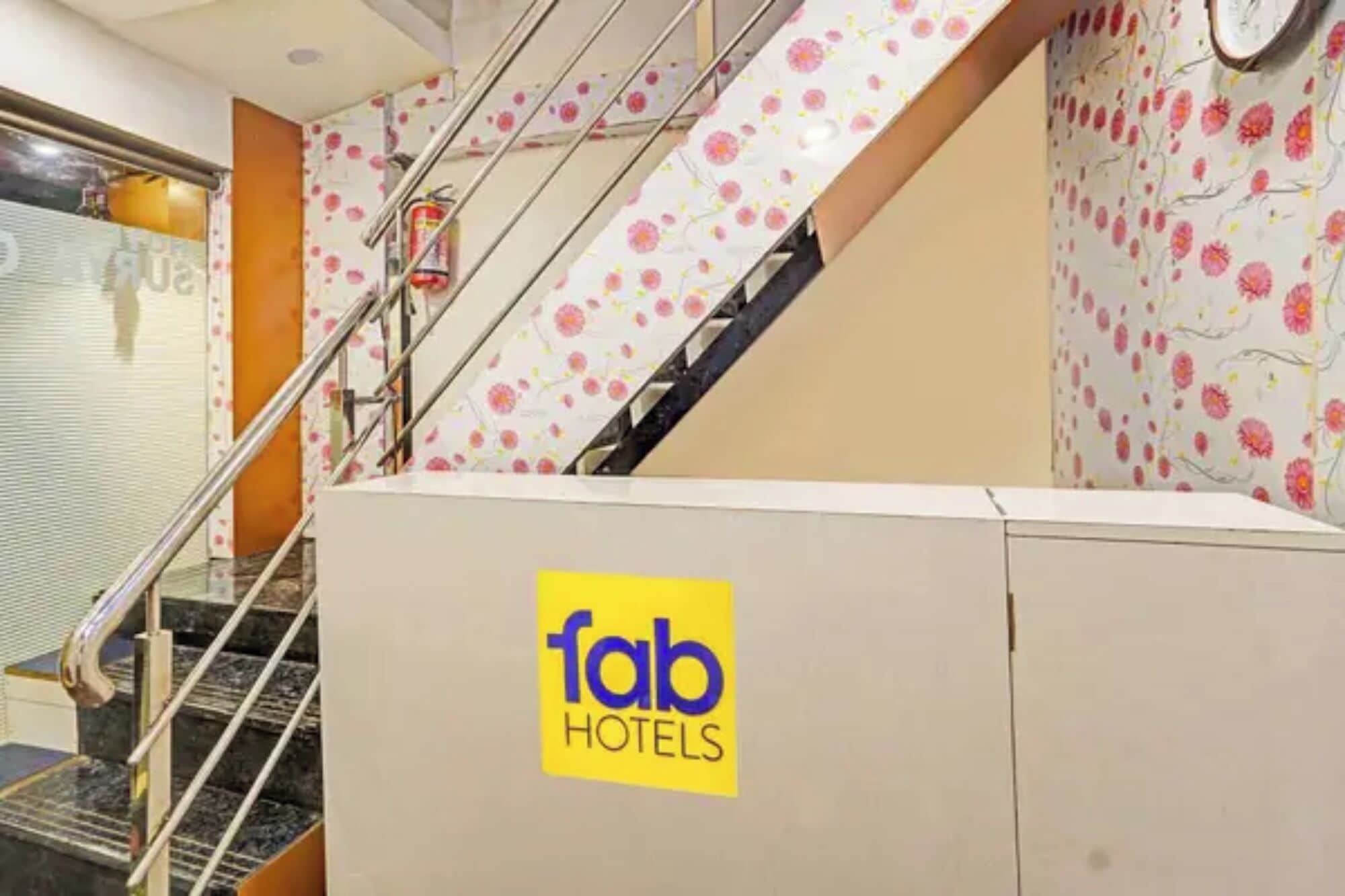 Interior de hotel con una escalera, un extintor y un cartel de Fab Hotels.