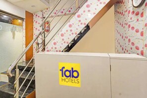Interior de hotel con una escalera, un extintor y un cartel de Fab Hotels.