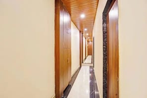 A hallway with wooden doors and a marble floor. - Via Surya Grand (Mumbai)