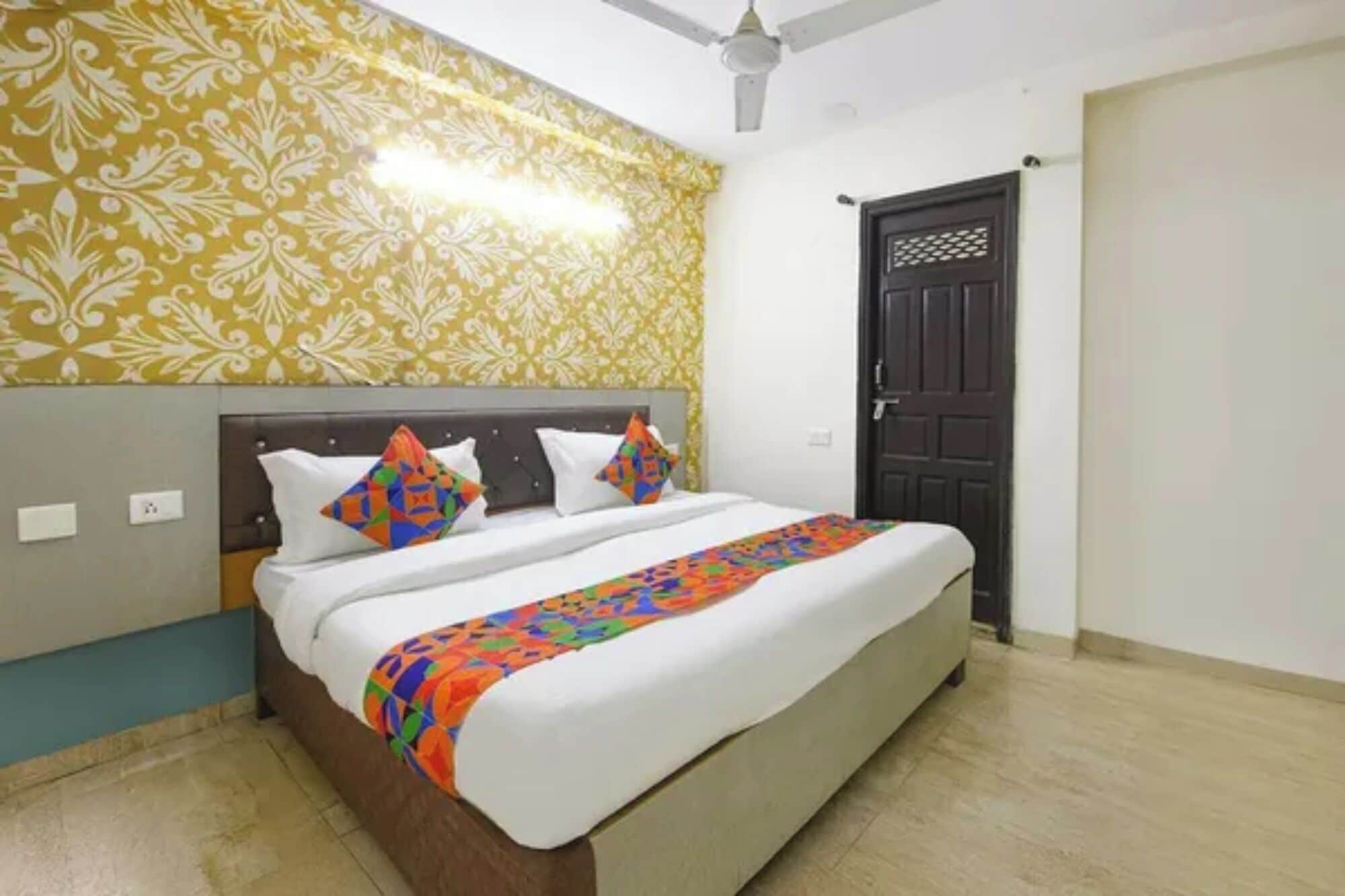 A hotel room with a bed, a ceiling fan, and a door.