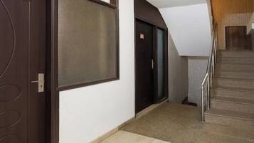 Un pasillo con una puerta, una pantalla montada en la pared y una escalera.