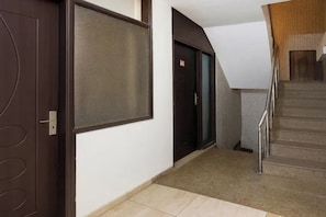 Un pasillo con una puerta, una pantalla montada en la pared y una escalera.