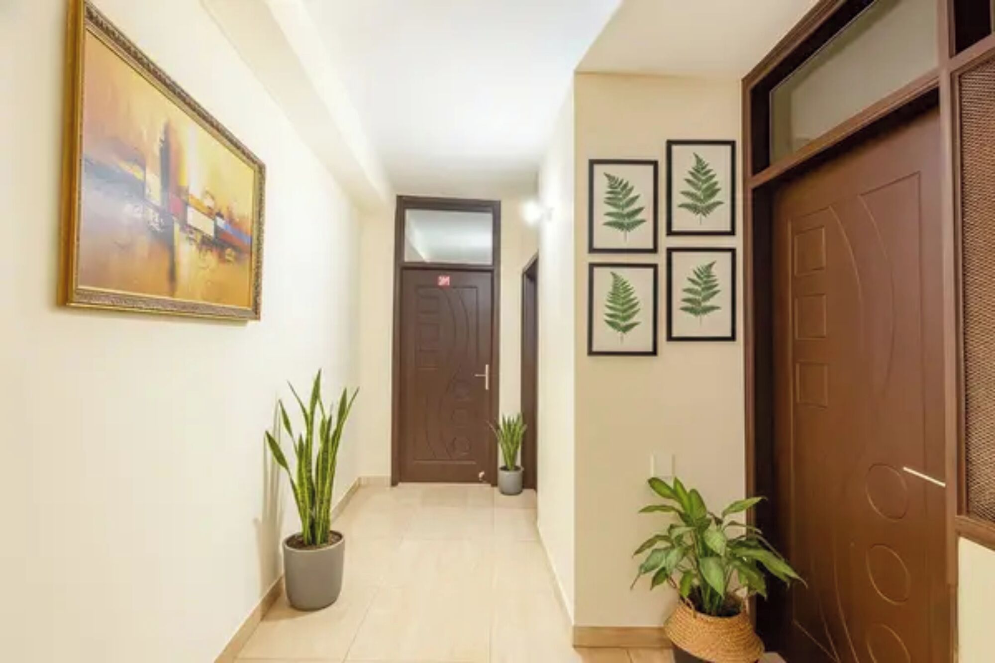 A hallway with a door, a framed painting, and potted plants.